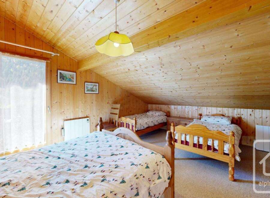 This charming property features a cozy bedroom with wooden paneling, creating a warm and inviting atmosphere.