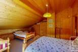 This charming bedroom features a cozy, wooden interior with a sloped ceiling, creating a warm and inviting atmosphere.