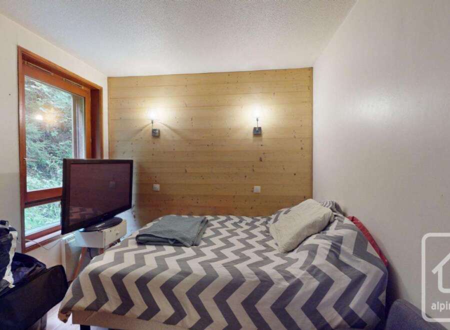 Discover this cozy bedroom featuring a stylish wooden accent wall and a comfortable bed with a unique patterned duvet.