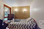 Discover this cozy bedroom featuring a stylish wooden accent wall and a comfortable bed with a unique patterned duvet.