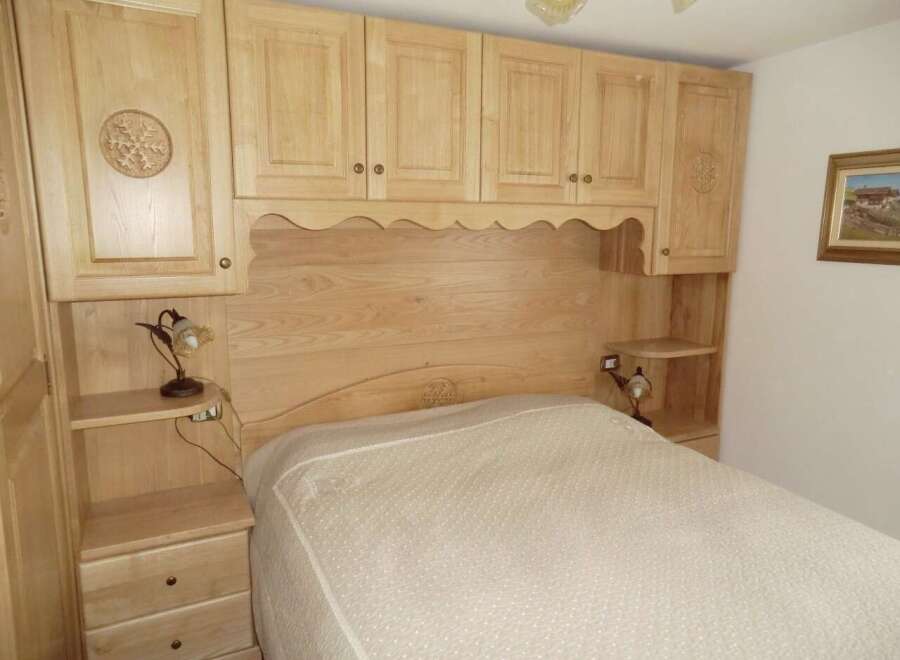 This cozy bedroom features custom wooden cabinetry and a built-in headboard, creating a warm and inviting atmosphere.