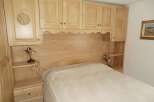 This cozy bedroom features custom wooden cabinetry and a built-in headboard, creating a warm and inviting atmosphere.