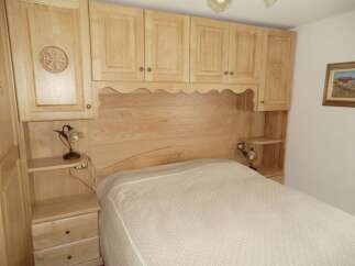 This cozy bedroom features custom wooden cabinetry and a built-in headboard, creating a warm and inviting atmosphere.
