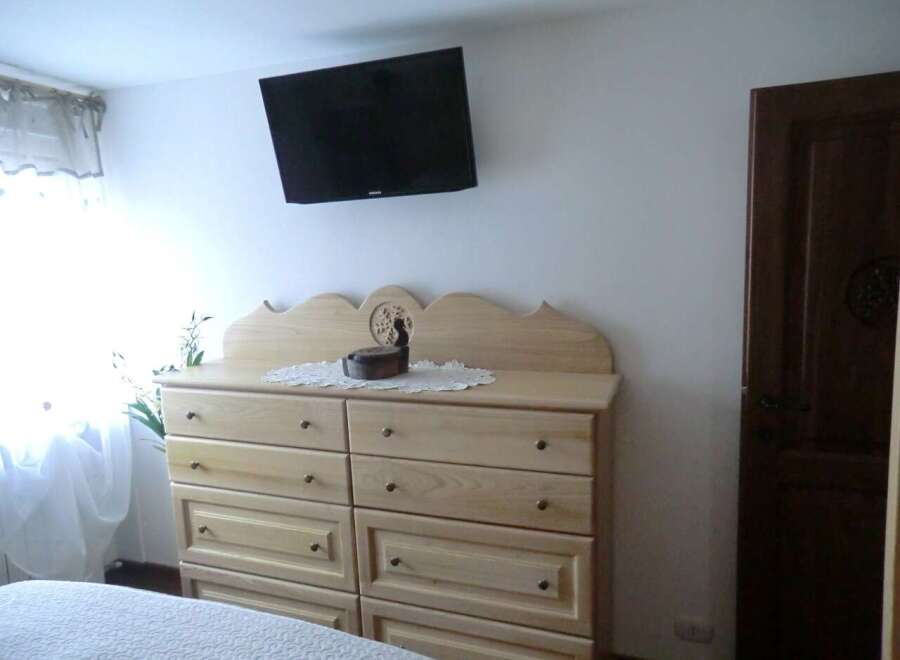 This charming bedroom features a stylish dresser and a wall-mounted TV, perfect for relaxation.