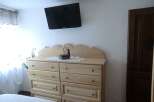 This charming bedroom features a stylish dresser and a wall-mounted TV, perfect for relaxation.