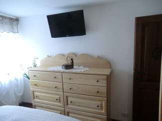 This charming bedroom features a stylish dresser and a wall-mounted TV, perfect for relaxation.