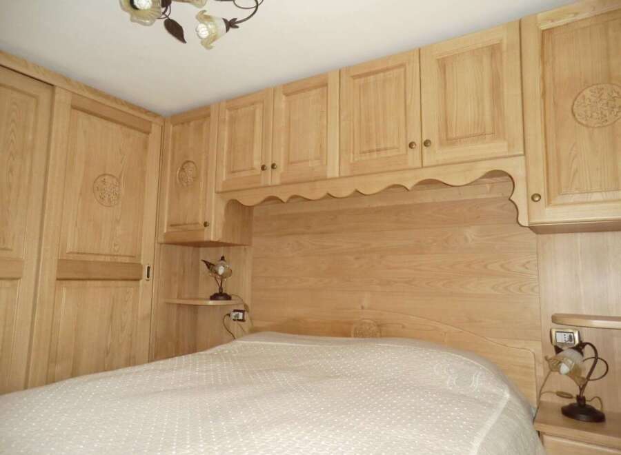 This bedroom features custom wooden cabinetry and a matching headboard, creating a cohesive and elegant design.