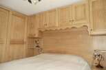This bedroom features custom wooden cabinetry and a matching headboard, creating a cohesive and elegant design.