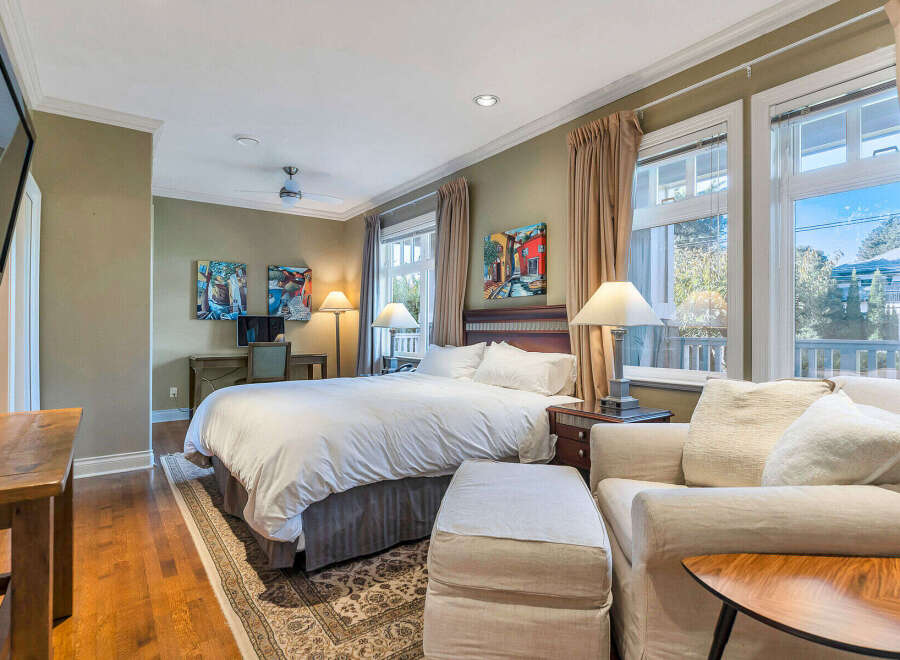 Step into luxury in this stunning bedroom, featuring a plush bed, a cozy seating area, and elegant artwork.