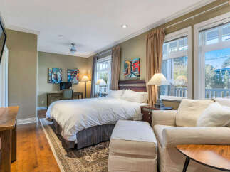 Step into luxury in this stunning bedroom, featuring a plush bed, a cozy seating area, and elegant artwork.