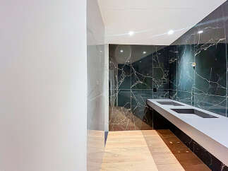 Step into luxury with this stunning bathroom featuring sleek black marble walls and a modern floating sink.