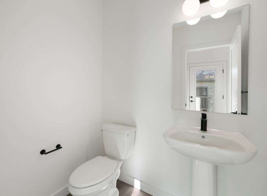 Step into this pristine powder room, showcasing a modern aesthetic with its clean lines and bright white palette.