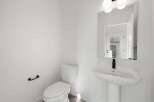Step into this pristine powder room, showcasing a modern aesthetic with its clean lines and bright white palette.