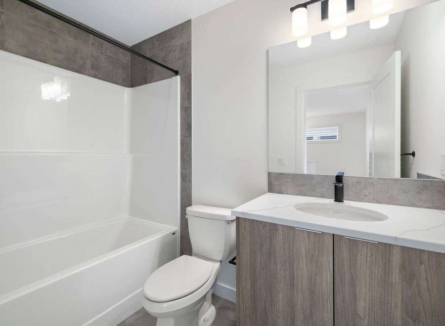 Step into this modern bathroom, featuring a sleek white bathtub and a stylish vanity with a marble countertop.