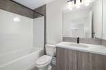 Step into this modern bathroom, featuring a sleek white bathtub and a stylish vanity with a marble countertop.