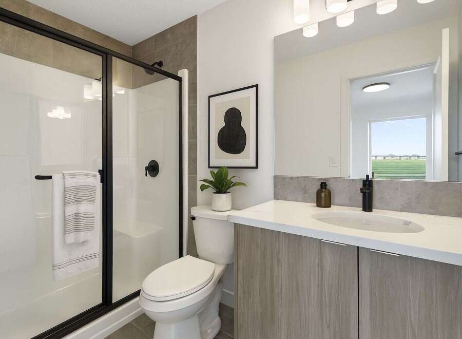 Step into a modern bathroom oasis! This stunning space features a sleek glass shower with black hardware, a stylish vanity with ample storage, and a contemporary design.