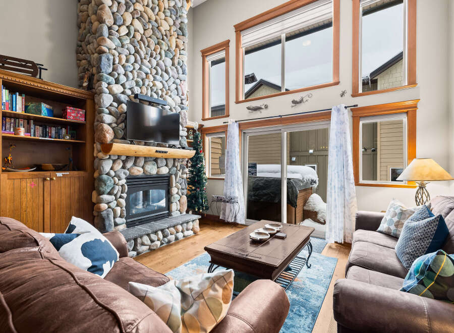 This stunning living room boasts a magnificent stone fireplace, creating a cozy and inviting atmosphere.