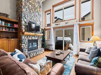 This stunning living room boasts a magnificent stone fireplace, creating a cozy and inviting atmosphere.