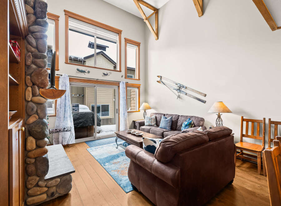 This stunning living room boasts a cozy ambiance with its stone fireplace and comfortable leather sofas.