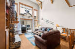 This stunning living room boasts a cozy ambiance with its stone fireplace and comfortable leather sofas.