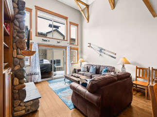 This stunning living room boasts a cozy ambiance with its stone fireplace and comfortable leather sofas.