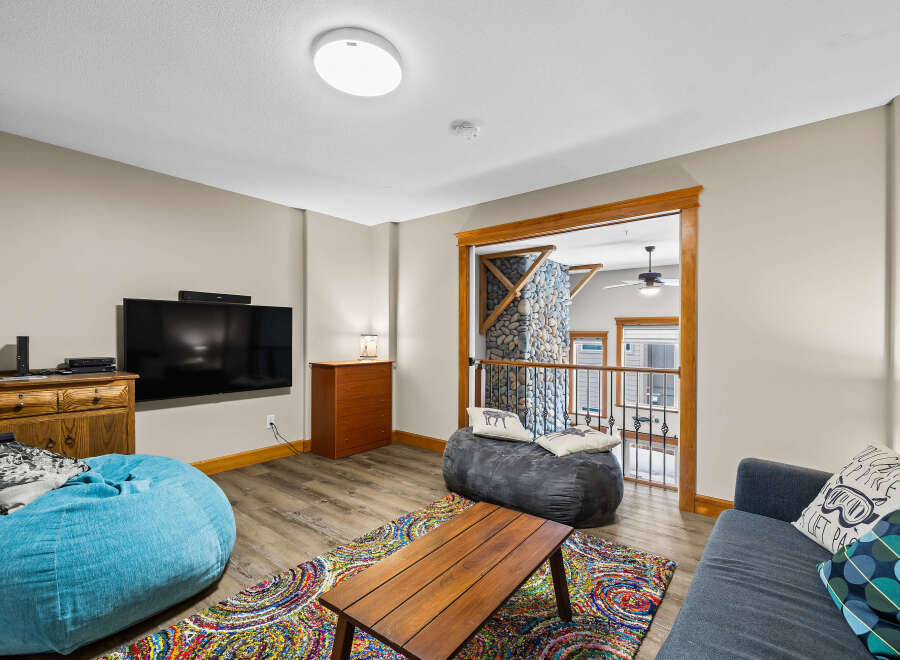This cozy living space features a modern entertainment setup with a large flat-screen TV and a stylish soundbar.