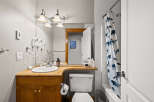 This charming bathroom features a warm wooden vanity with ample storage, complemented by a bright white sink and modern fixtures.