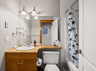This charming bathroom features a warm wooden vanity with ample storage, complemented by a bright white sink and modern fixtures.