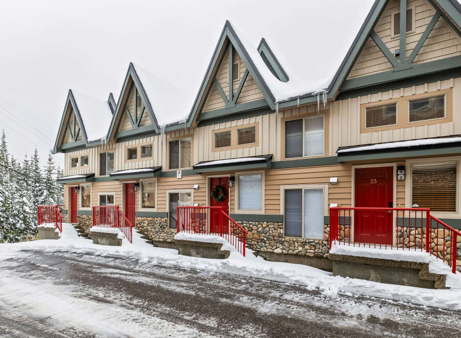 Charming townhomes nestled in a winter wonderland, offering a cozy retreat with stunning curb appeal.