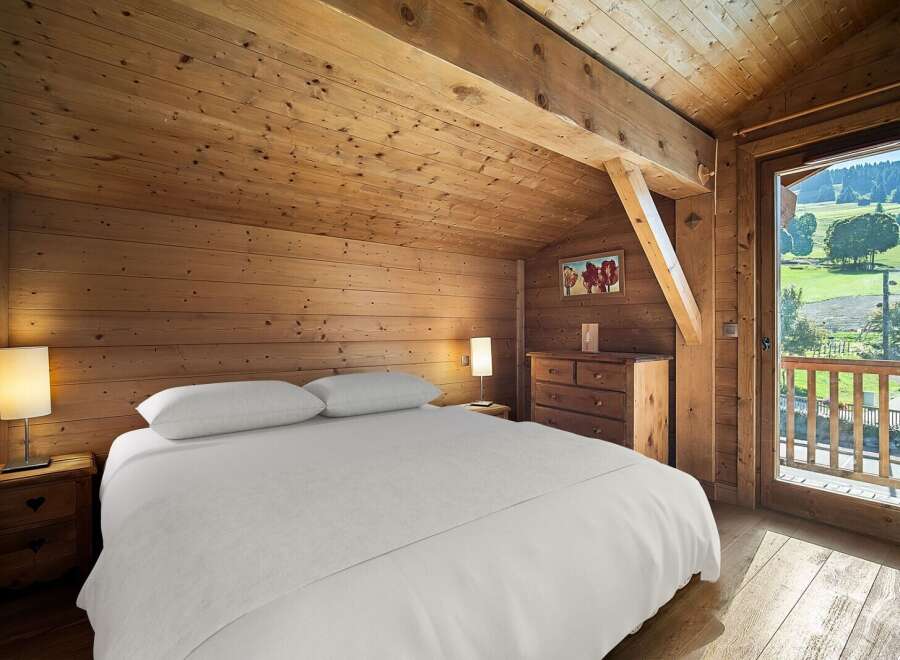 Experience rustic charm in this cozy bedroom, featuring warm wooden walls and a sloped ceiling.