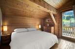 Experience rustic charm in this cozy bedroom, featuring warm wooden walls and a sloped ceiling.