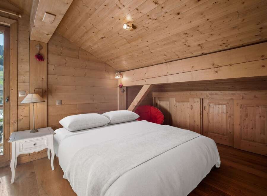 Experience the charm of this cozy bedroom featuring a wooden ceiling and walls, creating a warm and inviting atmosphere.