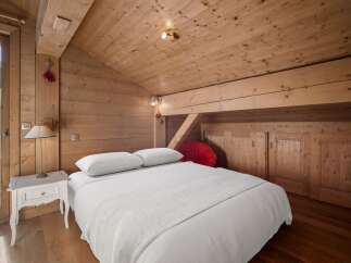 Experience the charm of this cozy bedroom featuring a wooden ceiling and walls, creating a warm and inviting atmosphere.