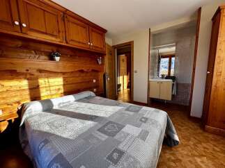Discover the charm of this cozy bedroom, featuring a beautifully crafted wooden headboard and matching cabinetry.