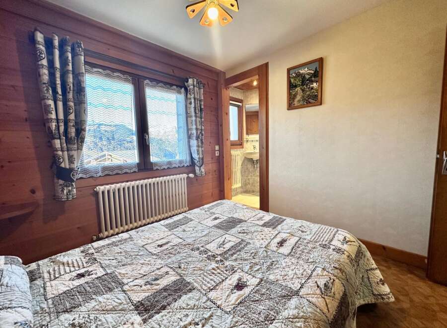 This charming bedroom features a cozy quilt, wooden accents, and a picturesque view through the window.