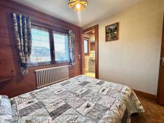 This charming bedroom features a cozy quilt, wooden accents, and a picturesque view through the window.