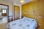 Discover the charm of this cozy bedroom, featuring a comfortable bed with a unique quilt and warm wooden paneling.