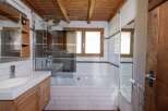 This charming bathroom features a rustic wooden ceiling and a modern white tiled design.