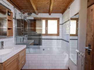 This charming bathroom features a rustic wooden ceiling and a modern white tiled design.