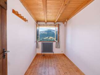This charming room offers stunning mountain views through a large window, creating a serene and inviting atmosphere.