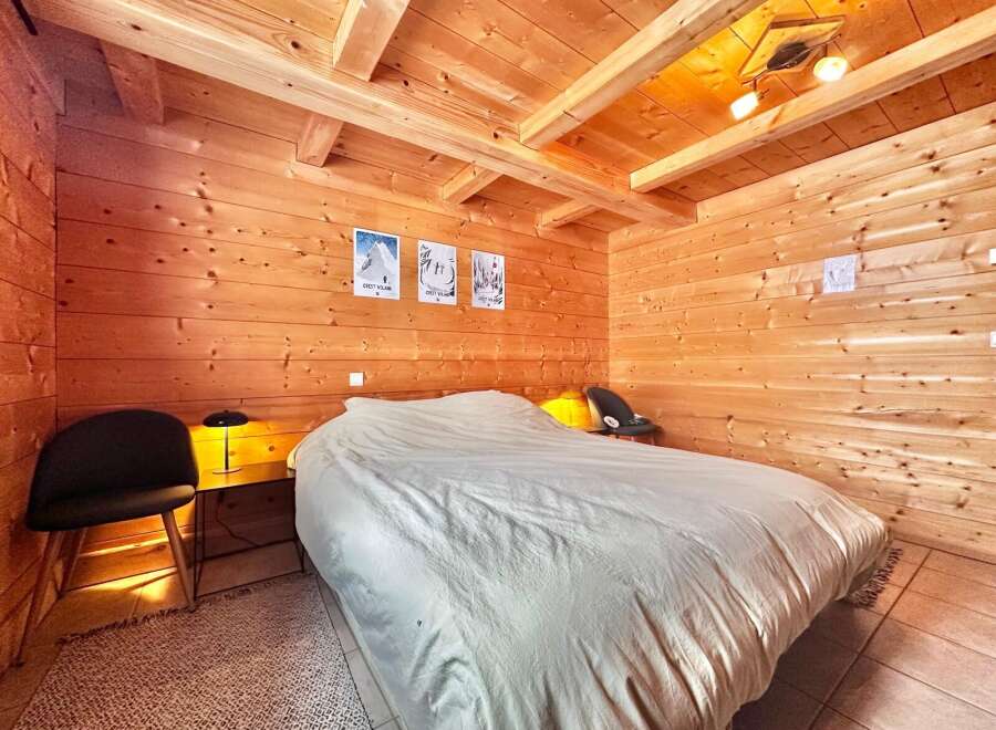 This cozy bedroom features beautiful wooden walls and ceiling, creating a warm and inviting atmosphere.