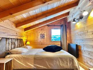 Experience the charm of this cozy bedroom featuring a rustic wooden interior and a comfortable bed.
