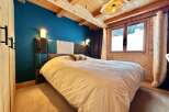 This cozy bedroom features a stunning wooden ceiling and a vibrant blue accent wall, creating a warm and inviting atmosphere.