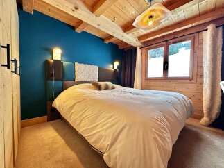 This cozy bedroom features a stunning wooden ceiling and a vibrant blue accent wall, creating a warm and inviting atmosphere.