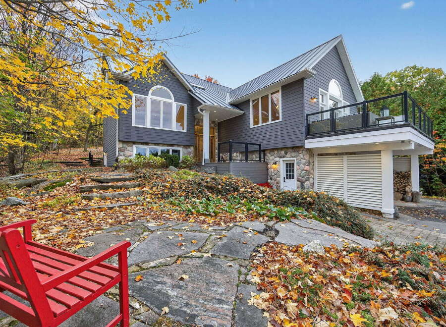 This stunning property boasts a modern design with a beautiful stone facade and a sleek metal roof.