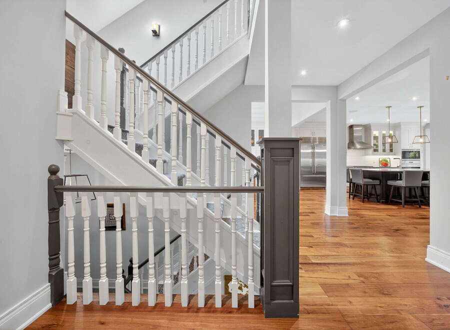 This stunning property features a grand staircase with elegant white balusters and a rich, dark wood handrail, creating a welcoming entrance.