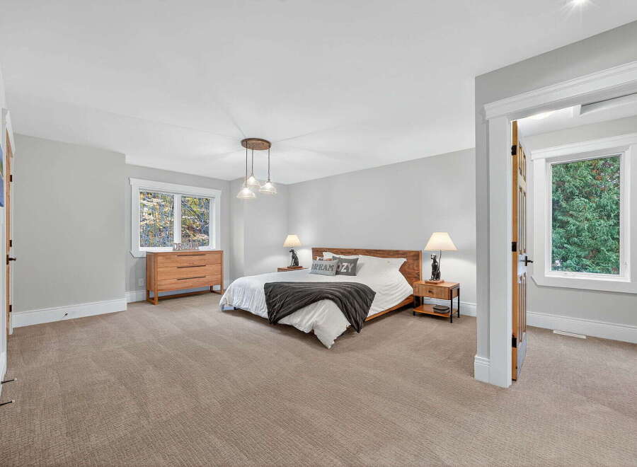 This spacious bedroom offers a serene retreat with its neutral color palette and ample natural light.