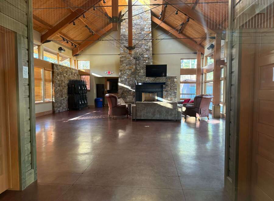 Step into this stunning lodge-style property, featuring a grand open space with soaring ceilings and exposed wooden beams.