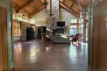 Step into this stunning lodge-style property, featuring a grand open space with soaring ceilings and exposed wooden beams.