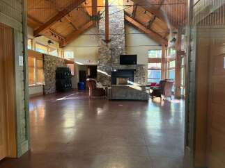 Step into this stunning lodge-style property, featuring a grand open space with soaring ceilings and exposed wooden beams.